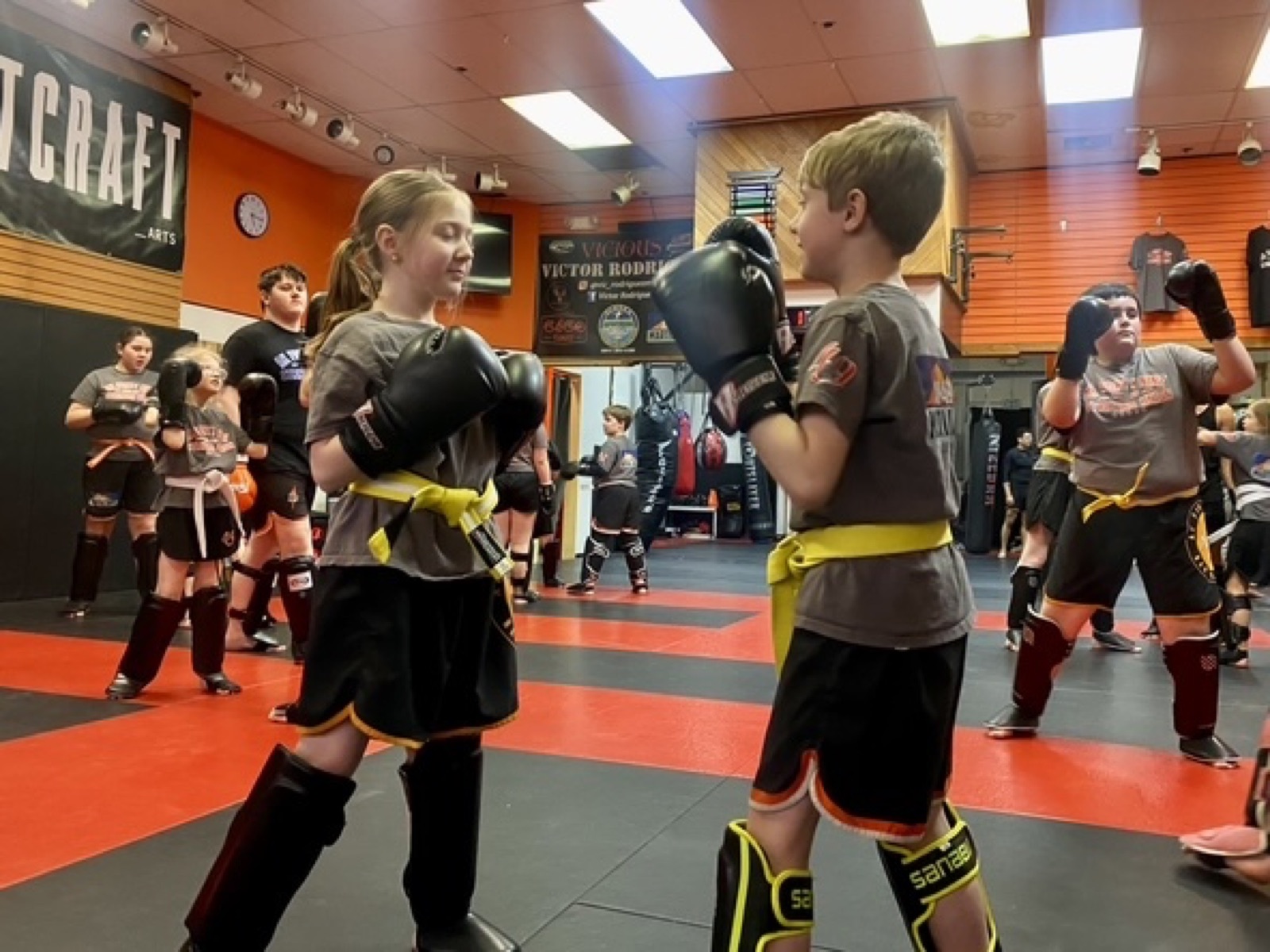 Kids in gloves and shin guards training Muay Thai in class at AK-49 Martial Arts