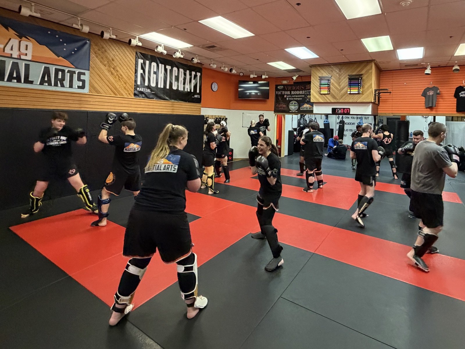 A kickboxing class at AK-49 Martial Arts working in pairs on the red and black mats