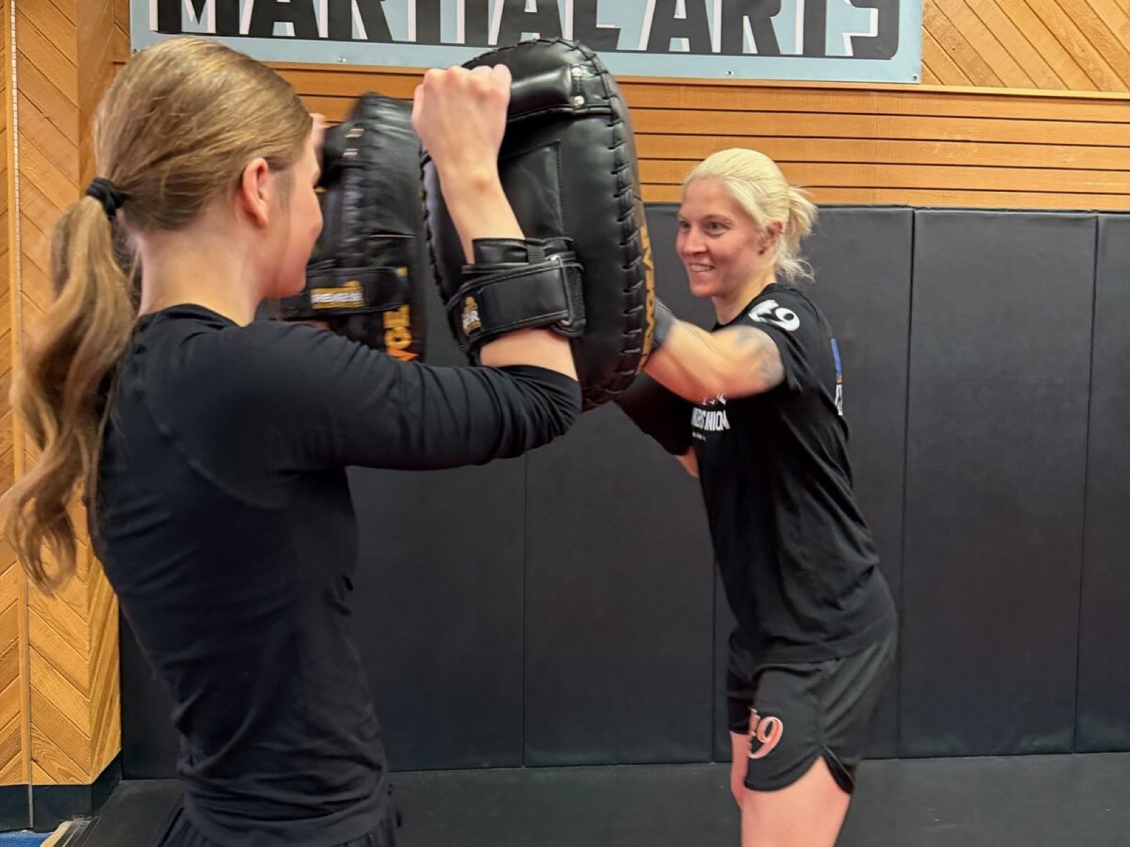 Two adult students doing partner pad work in a Muay Thai class under the AK-49 Martial Arts banner
