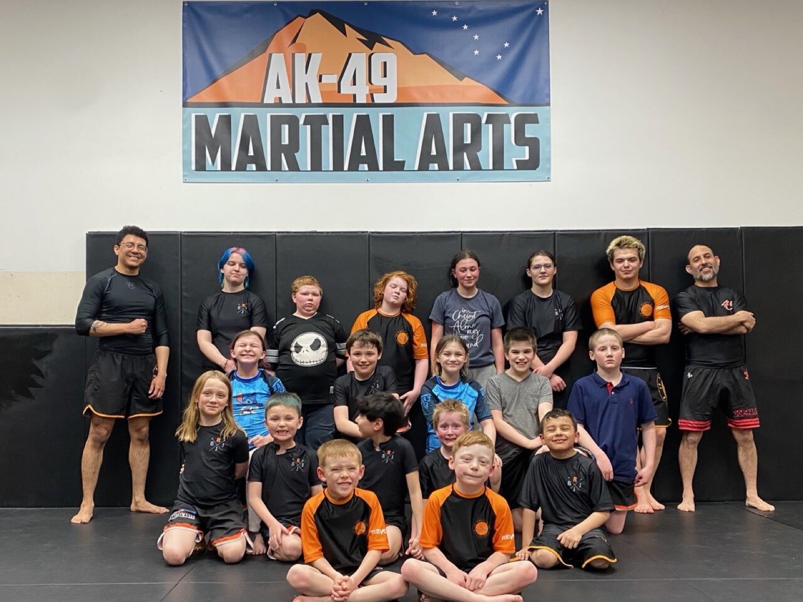 A big group of kids and coaches standing together under the AK-49 Martial Arts banner